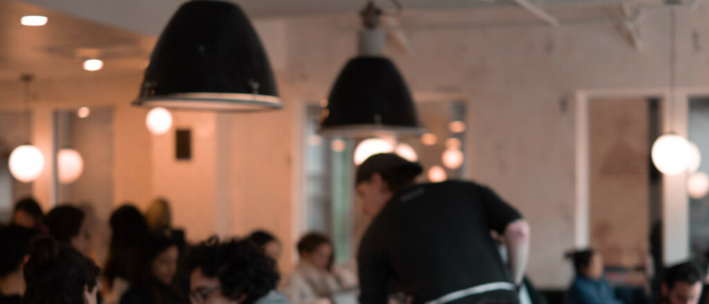 Waiter tending patrons in a busy cafe setting